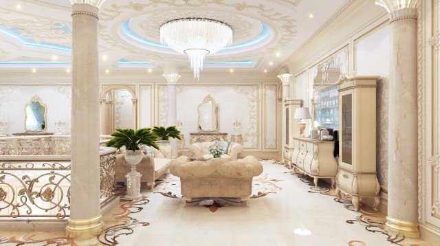 This picture shows a luxurious living room with a white, tufted sofa and loveseat with gold accents. There is a large rectangular coffee table with a white marble top in the center of the room. The walls are painted a soft cream color, and there are elegant drapes framing the windows, along with elaborate sconces for lighting. To the right is a grand fireplace, complete with a beautiful marble hearth and mantle. On either side of the fireplace are tall bookcases, and at the far end of the room is a glass french door leading out to the terr