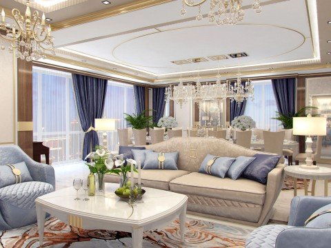 This picture shows a luxurious living room with a contemporary design. The room features elegant white furniture, a large chandelier, and several wall mounted artwork pieces. The walls are painted in an off-white color that helps to brighten the room. The central feature of the room is the large white sofa, which includes several throw pillows for added comfort. There is also a black accent table next to the sofa, which provides a stunning contrast to the overall look of the room.