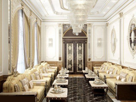 This picture shows an opulent interior space. It features gold leaf wall panels, rich wood paneling and accents, ornate plaster crown molding, and an intricately detailed ceiling. The room is also filled with art deco style furniture, including a grand chandelier, a large round table and plush armchairs. The overall effect is one of luxury, elegance, and sophistication.