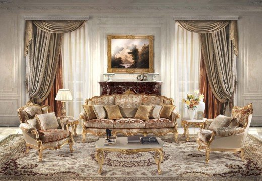 This picture is of a luxurious modern living room that features cream and beige colored walls and flooring. The room has several pieces of sleek, comfortable seating including a chaise lounge and a large sectional couch. There is also a large area rug in the center of the room with intricate designs. The room is decorated with a few accent pieces, such as a teal colored ottoman, potted plants, and a decorative mirror that hangs on the wall. In the corner of the room is a fireplace, which provides a cozy feel to the room.