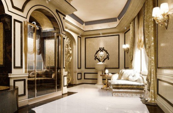 This picture shows a modern, luxury living room with high ceilings, sleek marble floors and floor-to-ceiling windows. The walls are covered in a beige and cream striped pattern, and the furnishings are all white and gold. A large, circular sofa takes center stage in the room, accented by two tall white chairs and a white coffee table. There is also an abstract art piece on the wall and a few standing lamps for lighting.