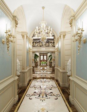 This picture shows an ornately designed hallway with white-tiled flooring and a grand marble staircase in the center. The walls are painted a light yellow color, and decorated with an intricate pattern of gold lines. The balcony overlooks the hallway from the second floor, with a modern chandelier hanging from the ceiling above it. There is an exquisite flower arrangement in a vase near the base of the stairs, and tall windows with detailed shutters line the walls.