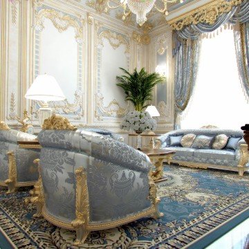 This picture shows a luxurious bedroom with a dramatic canopy bed featuring intricate carved detailing. The bed is situated in the center of the room, surrounded by classic decor elements such as patterned wallpaper and an ornate floor-length mirror. There is a chaise lounge with a velvet throw pillow and two nightstands on either side of the bed, each adorned with elegant table lamps. The room is well-lit with several recessed light fixtures, and there is a large rug on the hardwood floor that pulls the entire look together.