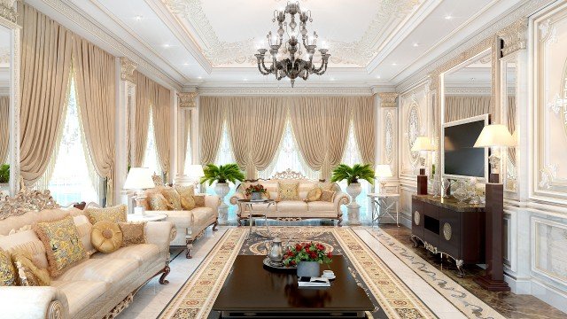 This picture shows a luxurious contemporary living room. The flooring is made of light-colored marble with a chevron pattern, and the walls are a warm beige color with a detailed white trim. A large sectional sofa dominates the space, accompanied by two white armchairs and two light brown ottomans. A mosaic patterned rug provides a focal point for the space, and a custom-made wall unit frames the television. The room also features a marble-topped side table and several potted plants for a touch of greenery. Overall, this modern living room