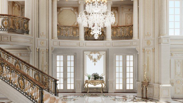 The picture shows a luxurious, modern living room decorated with golden accents and featuring a beige, tufted leather sofa, a white marble table with two armchairs, a large area rug, and a crystal chandelier hanging from the ceiling. The walls are also adorned with different kinds of artwork and decorative sculptures.