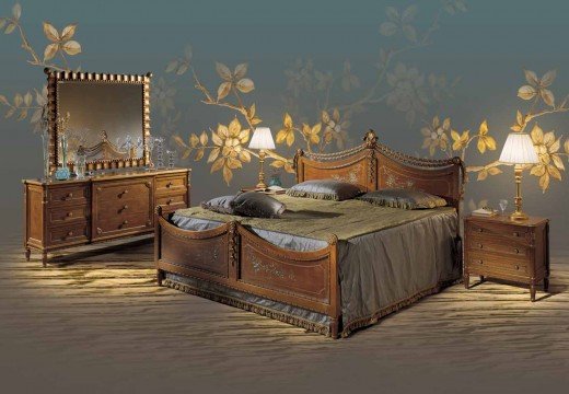 The picture shows a luxurious master bedroom with a canopy bed, featuring elegant decorations in classic ivory and gold colors. The bed is adorned with a sumptuous cream-colored duvet and white pillows, while the walls and ceiling are a deep shade of gray. A soft rug covers part of the wooden floor, and a black leather armchair is placed in one corner of the room. Various decorative pieces, such as a mirrored wall sconce and a large gold-framed painting, add to the classy look of the bedroom.