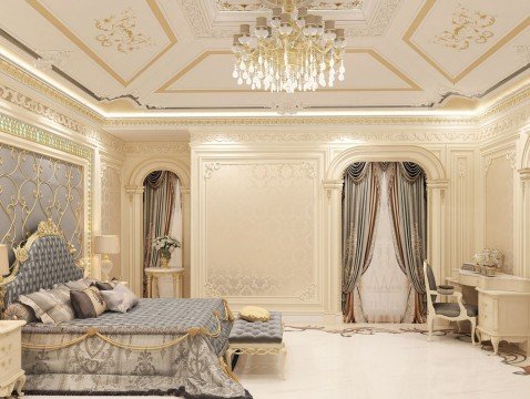 This picture shows a lavish, open-concept living space. The room is filled with luxurious furniture and decor, including a large brown leather sofa, various armchairs, a coffee table, and a grand fireplace. The walls are adorned with multiple pieces of artwork and a grand chandelier hangs from the center of the room. Smooth, marble-like tiles line the floor and the overall color scheme of the room leans towards neutral tones.