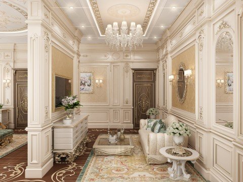 This is a picture of a luxurious, high-ceilinged room with an elegant modern design. The walls are a light cream color and the center of the room features two tall marble pillars flanking a large decorative mirror with a gold frame. There is a white leather couch in the center of the room, and a red and gold carpet lays across the floor. A crystal chandelier hangs from the ceiling and is reflected in the mirror.
