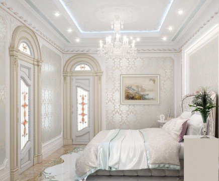 This picture shows a luxurious master bedroom with a unique and incredibly detailed design. The walls of the bedroom have golden-brown wallpaper with ornate and abstract designs, which are complemented by white crown molding and dark wood flooring. An impressive four-poster bed, upholstered in a cream-colored fabric with an ivory headboard, sits prominently in the center of the room. To the right of the bed is an antique-looking table, topped with a beautiful golden-framed painting. The style of this bedroom is classic and elegant, with a hint of op