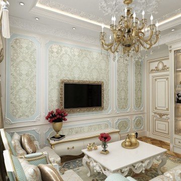 This picture shows a luxurious modern living room with two white leather sofas and armchairs situated around a gray rectangular coffee table with gold accents around its edges. The walls and ceiling are white with a unique plasterwork design in each corner of the room. A large decorative mirror is mounted on the wall between the two sofas, and a round black accent table with a white vase full of blooms stands by the window. The room also features an ornate crystal chandelier and several pieces of stylish art hung on the walls.