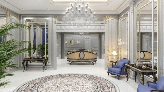 This picture shows a luxurious interior hallway showcasing a grand staircase leading up to a second-story balcony. The walls are adorned with intricate wall decor, and marble floors add a touch of elegance to the design. A glass chandelier hangs from the ceiling, while a bench positioned beneath the stairs provides a place of respite. Several beautiful potted plants line the walls, adding a touch of greenery to the elegant space.
