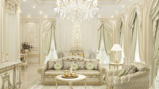 This picture shows a grand, luxurious-looking living room in an Arabian style. The walls are painted in an off-white color, and the floor is made of marble. The furniture is ornately decorated and consists of a large white leather couch, two wooden chairs with intricate designs and a dark rug. There is a large, ornate window in the background, and several decorative pillows on the couch. An exotic plant adds to the decor, bringing life and color to the room.