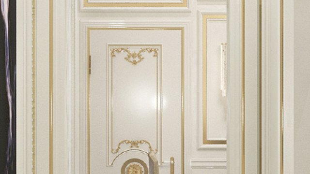 This picture shows an elegant entrance hallway and stairs inside a luxurious home. The walls are painted white and covered in decorative crown molding and sconces, while the hardwood floors have a dark finish and intricate designs. At the top of the stairs is a grand chandelier with gold accents and a round window that provides a view of the outside.