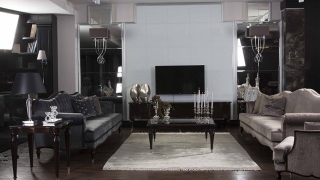 Modern living room with neutral color palette, featuring a tufted couch, two armchairs, and a fireplace with built-in shelves.