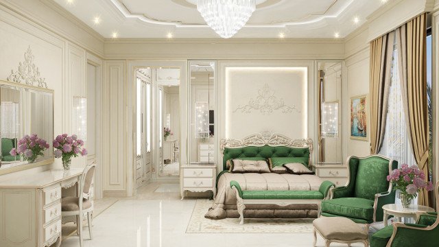 This picture shows an opulent and luxurious bedroom. The room features a white marble floor, with a large, tufted bed in the center decorated with plush pillows and a light-gold throw blanket. The walls are done in a muted grey and light blue pattern, and the bed is surrounded by wall-mounted lamps with beaded crystal shades. To the right, a beautifully carved dresser holds a set of tall vases filled with fresh flowers and a tray with a few decorative items. On the left, two upholstered chairs sit on either side of a round,