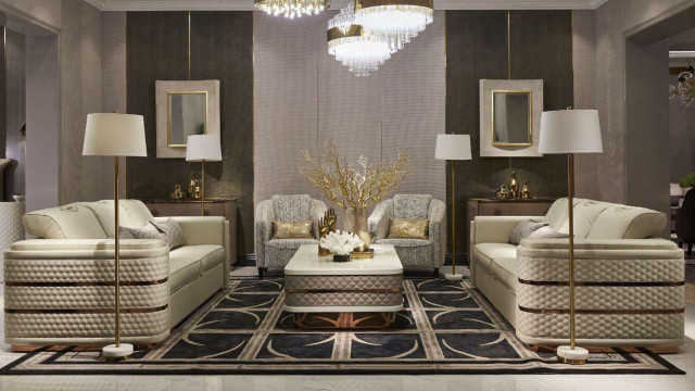 A symmetrically designed modern living room featuring a white grand piano with an elegant chandelier overhead, surrounded by patterned furniture and area rugs.