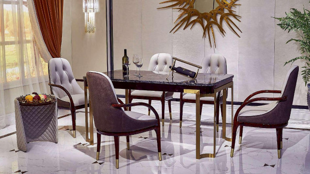 The picture shows a modern luxury dining room with gold and white accents. It has a white table with sleek gold legs and seating for six, surrounded by eight gilded chairs. On the walls are ornate chandeliers and large mirrors. The floor is tiled in a white and gold pattern, and the ceiling is intricately painted.