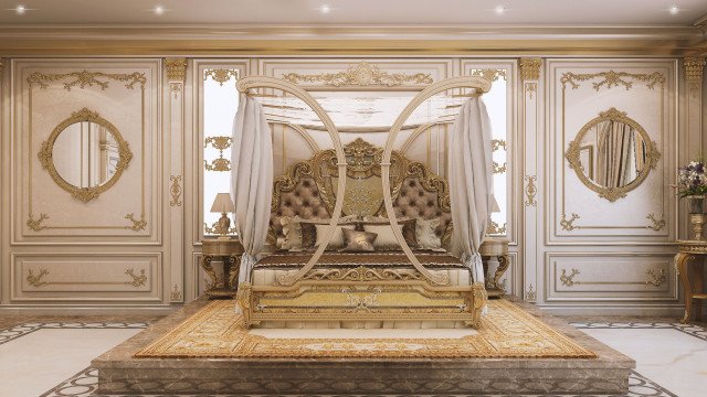 This picture shows a luxurious master bedroom designed in an elegant modern style. The walls are decorated with gold accents and patterns, while the headboard and nightstands have intricate detailed carvings. The bed is upholstered in white fabric and is framed by a pair of beige armchairs. The room is illuminated by two large crystal chandeliers, while various plants and flowers add a touch of color and life to the decor.