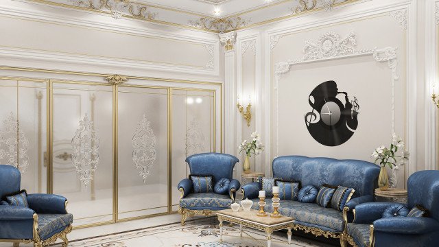 This picture shows a luxurious living room in shades of cream and gold. It features a large, upholstered sofa with ornate arm details and matching accent chairs. The walls are decorated with an intricate floral wallpaper, while the ceiling is adorned with sparkly chandeliers. The flooring is finished with a dark hardwood, and the room is complete with white sheer curtains.