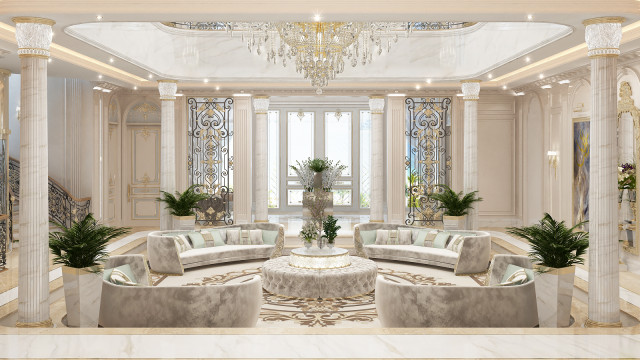 This picture shows a large and luxurious dining room interior designed in a modern style. The room features a long white marble dining table with upholstered chairs, a crystal chandelier, a white fireplace with a marble mantelpiece, and several beige armchairs. Various pieces of artwork hang on the walls, and the floor is covered with a beautiful patterned rug.