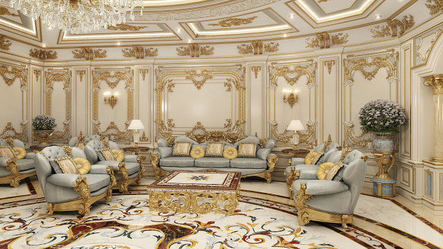 This picture is showing a modern, luxurious living room. It features two white armchairs and a cozy sofa in the center, which are positioned around a black and gold coffee table. The walls are painted a light grey and feature a number of modern abstract art pieces, as well as recessed lighting. The floor is a dark wood, with a white and beige striped area rug pulled up in front of the seating area.