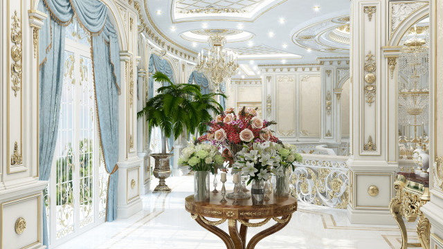 This picture shows a modern and luxurious living room with a white and gold color scheme. It features a curved white sofa sitting against a white wall adorned with wall art. The seating area has two white chairs, a glass coffee table, a white rug and two small round marble tables. The walls are decorated with gold accents, including gold-framed mirrors and large wall sconces. There is a black and white abstract painting on the wall above the sofa.