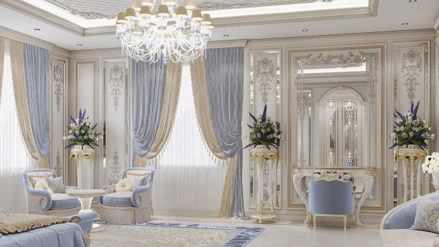 This picture shows a modern luxury living room designed by Antonovich Design. It features a brown tufted leather sofa, a white marble coffee table, and several blue and cream velvet pillows for added comfort and style. The walls are painted in a light beige color, with several framed pieces of art hanging on the walls around the room. A black, white, and gold abstract area rug covers the center of the room, while two large windows provide plenty of natural light into the space.