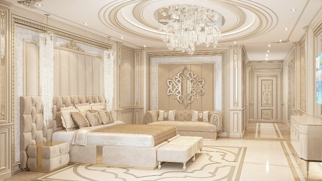 This picture shows a luxury bedroom designed by Antonovich Design. The wall has a metallic finish, and a large chandelier hangs from the ceiling. The room is decorated with an upholstered bedframe in a beige fabric and a beige area rug. The walls are painted in a soft white hue, and two nightstands are placed on either side of the bed. The nightstands are topped with decorative lamps and accented with modern art pieces. On the wall, a gold framed mirror sits above a dresser with a wide marble top.
