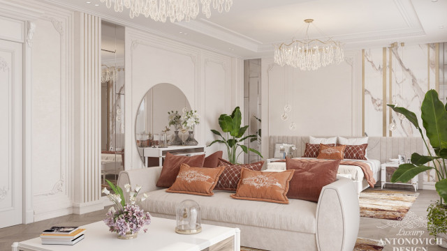A spacious and luxurious living room with white furniture and a lavish wallpaper pattern in shades of beige.