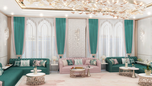 This picture shows an interior design created by Antonovich Design. It features a luxurious living room with a modern look. The walls are painted in a soft pink hue, with grey and white accents in the furniture, curtains and decorative elements. There is a patterned carpet on the floor, and a large window to let in natural light. A sofa and armchairs are arranged around a white and metal coffee table, and a variety of potted plants add green accents.