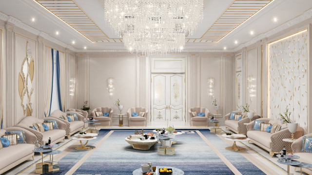 This is a picture of a luxurious living room with white marble floors, crystal chandeliers hanging from the ceilings, and plush ivory furniture. There is a large white sectional sofa with coordinating armchair and ottoman, a coffee table with tufted upholstery, and a decorative glass cabinet with intricate details. The walls are decorated with gold trim designs and detailed artworks.