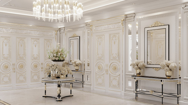This picture shows a luxurious and modern living room. The room features comfortable white leather seating, an ornate marble fireplace, and beautiful chandeliers hanging from the white tray ceiling. There is also an intricate patterned rug on the floor and a grand staircase leading to the second floor. The walls are decorated with artwork and a unique mirrored display cabinet.