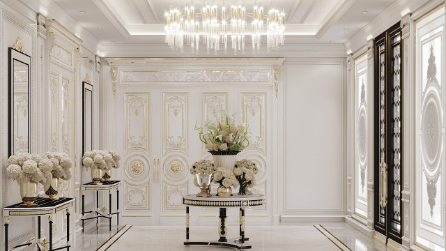 This picture shows a luxurious modern living room designed by Antonovich Design. It features a large white leather sofas with black and gold accents, a marble fireplace, and an exquisite crystal chandelier in the center of the room. There are also two large plants, adding a bit of nature to the design. The walls and floors are adorned with intricate wallpaper, as well as marble and wood flooring.