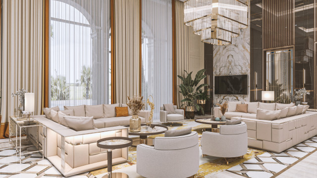 This picture is of a modern and luxurious living room, featuring a beige leather sectional sofa, with two accent armchairs. The walls are in a light cream color, and the curtains are made of a sheer golden material. A large, rectangular window allows natural light to fill the space. In the center of the room an oval-shaped coffee table sits atop a white rug, with a colorful floral arrangement as its centerpiece. In the background, a large gold chandelier hangs from the ceiling, providing an elegant and glamorous touch to the overall design.