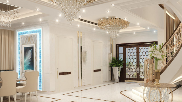 A grand entrance hall with ornate architecture and luxurious décor, featuring a crystal chandelier, marble walls and floor, and a red-carpeted stairway.