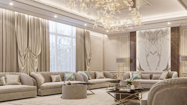 This picture shows a modern living room designed with luxury materials. Featuring a marble floor, high ceilings with elegant crown moldings, modern furniture upholstered in rich fabrics, and an exquisite white stone accent wall that serves as a centerpiece of the entire design. The room is tastefully accessorized with intricate light fixtures, a statement mirror, and a stunning golden chandelier.