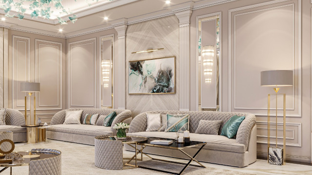 This picture is showing a luxurious and modern living room with a variety of comfortable seating options. It features an off-white sofa, two upholstered arm chairs, a glass coffee table, an ottoman, and a beautiful rug with geometric pattern. Accentuating the neutral furniture is a unique wall piece that appears to be a painting on canvas. On either side of the sofa are two tall standing lamps with decorative drum shades. The overall feel of the room is contemporary and stylish.