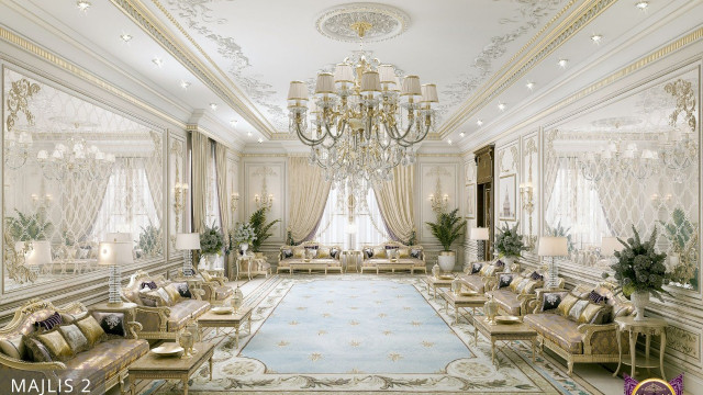 This picture shows a classic and luxurious living room. It features a large white sofa with gold accents and a unique marble coffee table sitting in front of it. The walls are painted in a bright pastel blue while the rug is in a beige hue, giving the room an air of sophistication. The large window on the right allows natural sunlight to fill the room. Mirrors are affixed around the room, creating an expansive feel in the space. Plants can also be seen around the room, bringing in some natural greenery.