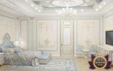 This picture shows an ornate luxury hallway. The hallway is adorned with marble walls and floors, detailed crown molding, elegant chandeliers, and stylish furniture. The gold and white hues give the hallway a regal and sophisticated look. It appears to be the perfect place to make a grand entrance.