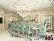 This picture shows a luxurious dining room with marble flooring, an ornate chandelier, and a mirrored ceiling. The walls are painted in a soft pastel shade with white trim and a golden moulding around the edges. There is a large round table in the center of the room with a set of four elegant chairs around it. On the table is a white centerpiece with a beautiful floral arrangement.