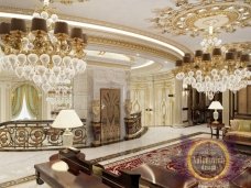 This picture shows an ornate ceiling in a room. The ceiling has intricate golden decorations and swirls that create an elegant, luxurious look. There are also small sparkling lights built into the ceiling which adds to the overall effect.