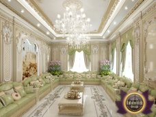 This picture shows an ornate hallway illuminated by a glimmering chandelier. The walls are lined with intricate moldings and the floor is tiled with a elegant pattern. A luxurious set of furniture completes the look, adding an element of sophistication to the space.