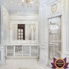 This picture shows a luxurious, marble bathroom with two elegant vanities flanking a large sink. There is a free standing bathtub in the middle of the room and a separate shower area with glass doors next to it. The vanity has ornate gold fixtures and an abundance of storage space. The overall look of the room is elegant and classic.