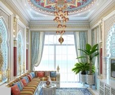 This picture is of a modern, luxurious interior design. It features a white, curved settee with ornate armchairs, a low coffee table, and a small end table in a white marble floor. The walls are painted a deep blue and the ceiling is adorned with intricately carved moldings and a stunning chandelier. A large arched mirror hangs on one wall, while the other wall displays an abstract artwork. The furniture pieces are all upholstered in a luxurious blue and gold velvet fabric which complements the overall color palette.