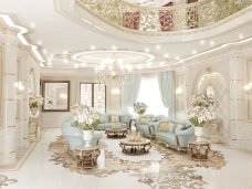 This picture shows a luxurious living room with an elegant design. The walls are painted in a light shade of beige, while the floor is covered with a white marble. In the center of the room is an ornate white sofa with gold accents, accompanied by two matching armchairs. The walls are decorated with large paintings, while the windows are dressed with sheer white curtains. A large crystal chandelier hangs from the ceiling, illuminating the space.