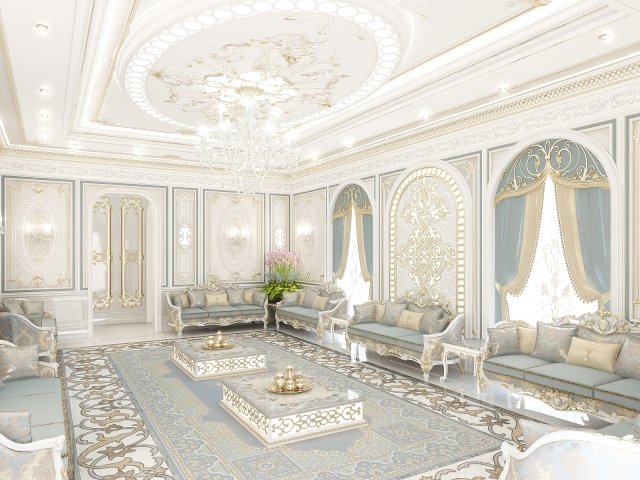The picture shows a luxurious modern living room. The room is full of opulent furniture and decorations, including a cream-colored leather sofa with a gold-accented throw and matching chairs, a modern white coffee table, and an ornate rug. A grand chandelier hangs from the ceiling, adding a touch of elegance. The walls are painted in a neutral beige colour and feature large, framed artworks. There are also several plants scattered around the room, adding a touch of nature to the contemporary setting.