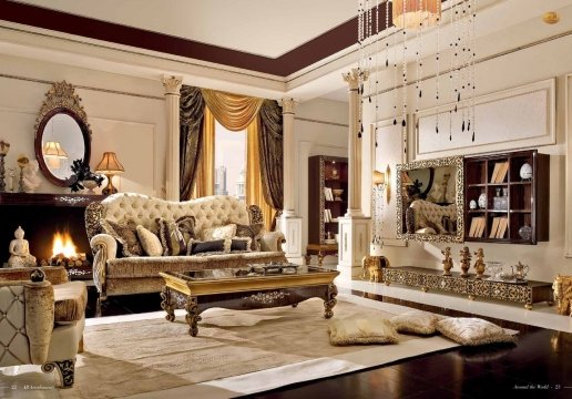 This picture shows a luxurious interior design with a central bubbling fountain surrounded by a rich paneled wall with two brightly-lit alcoves. The room features a contemporary fireplace and a pair of columns leading to the ceiling. The floor is beautifully tiled in a marble pattern with ornately decorated rugs centered around the focal fountain.