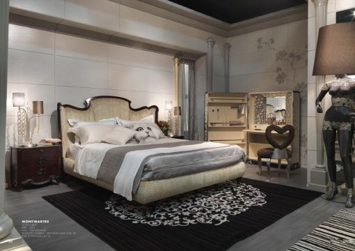 This is an example of a modern luxury bedroom designed by Antonovich Design. The room features a large bed with a headboard covered in luxurious gray upholstery. There are two nightstands on either side of the bed, and floor to ceiling curtains to provide privacy. The walls are painted a light gray color, and the floors are covered in a white marble patterned carpet. The room also includes several pieces of modern furniture, including a chaise lounge, armchair, and ottoman. Lastly, there are several lamps and candles placed throughout the room, providing a warm and
