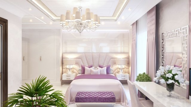 This picture shows a modern and luxurious bedroom design with a large bed. The bed is upholstered in white leather, and it has tall headboard and matching footboard that are adorned with gold trim. The bed is centered in the room against the wall which is covered in light gray wallpaper with a subtle geometric print. An ornate wall sconce hangs above the bed, and two nightstands flank either side of the bed. The room features a gray sectional sofa and area rug in addition to a mirrored dresser and a white armchair. The walls of the room are